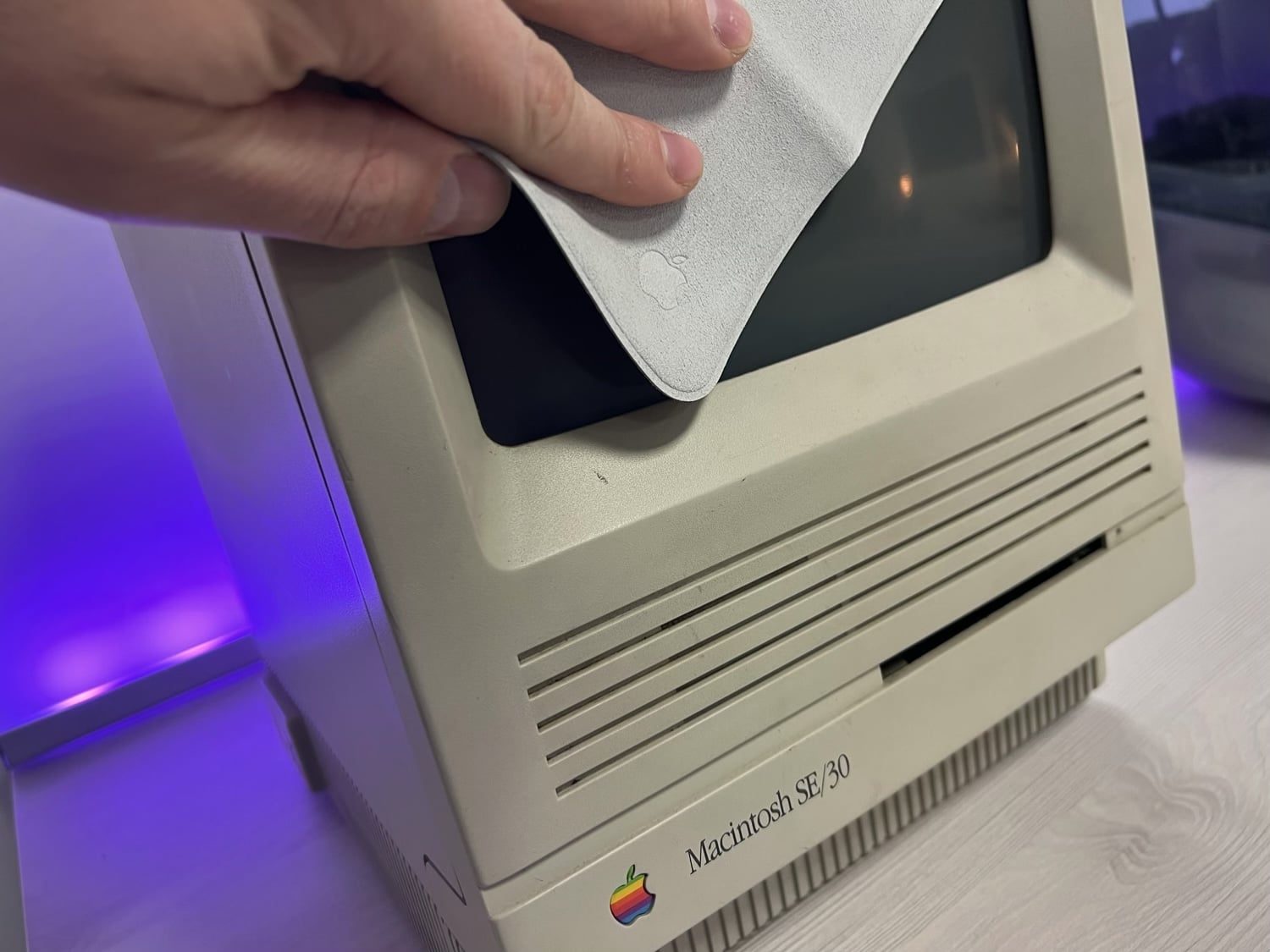 Hand wischt mit dem Apple-Poliertuch ein Mac-Display ab