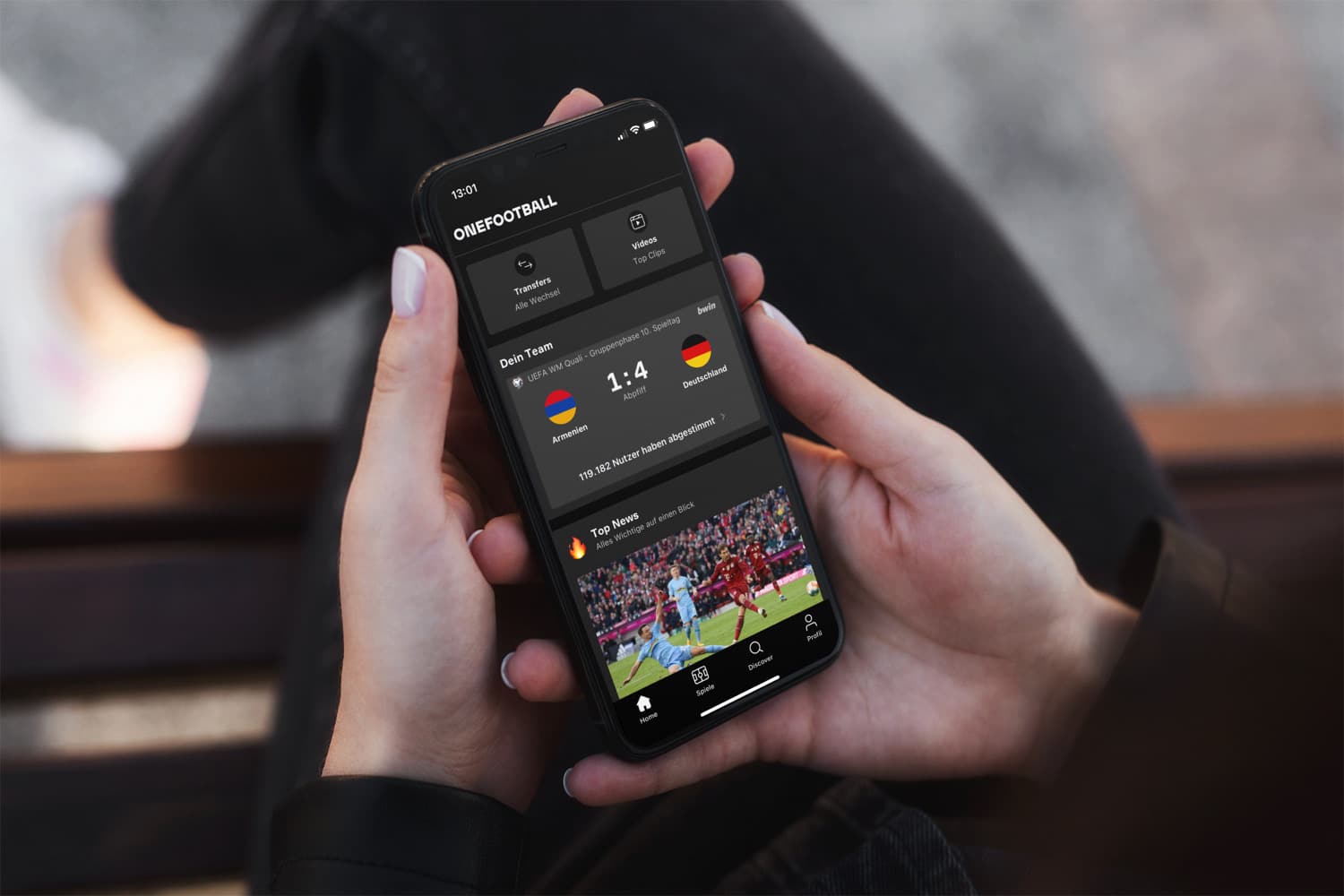 Eine Person hält ein iPhone mit geöffneter OneFootball-App in den Händen