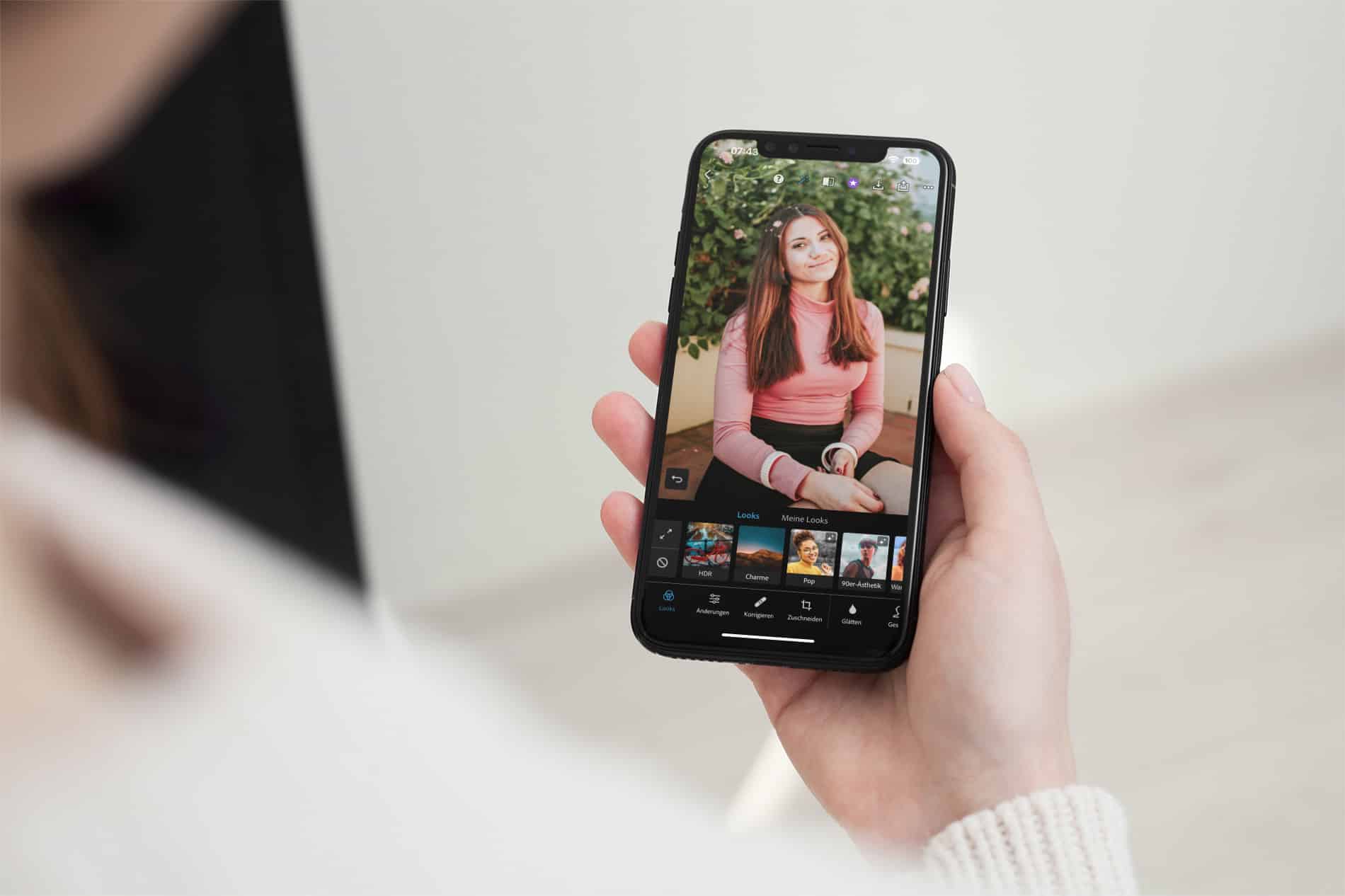 Eine Person hält ein iPhone mit geöffneter Adobe Photoshop Express-App in der Hand