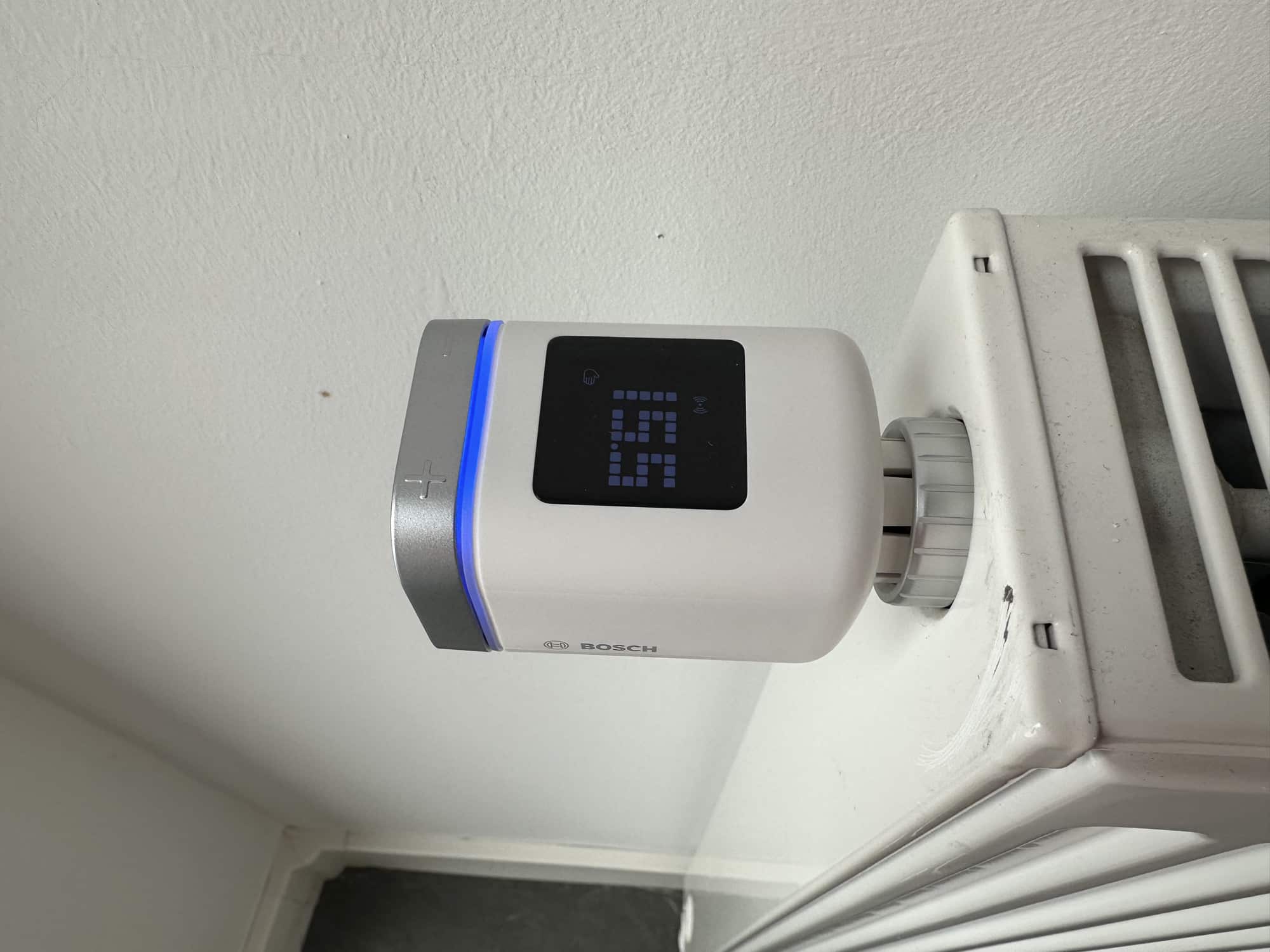 Bosch Smart Home Heizkörperthermostat II an der Heizung mit blauem Ring
