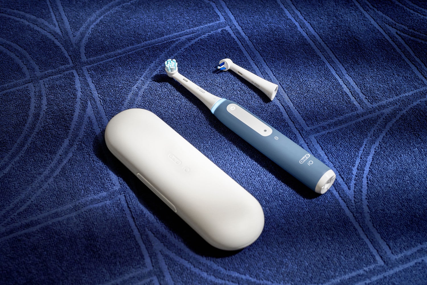 Oral-B iO MyWay in blau mit Reiseetui und Ersatzbürste auf einem blauen Handtuch