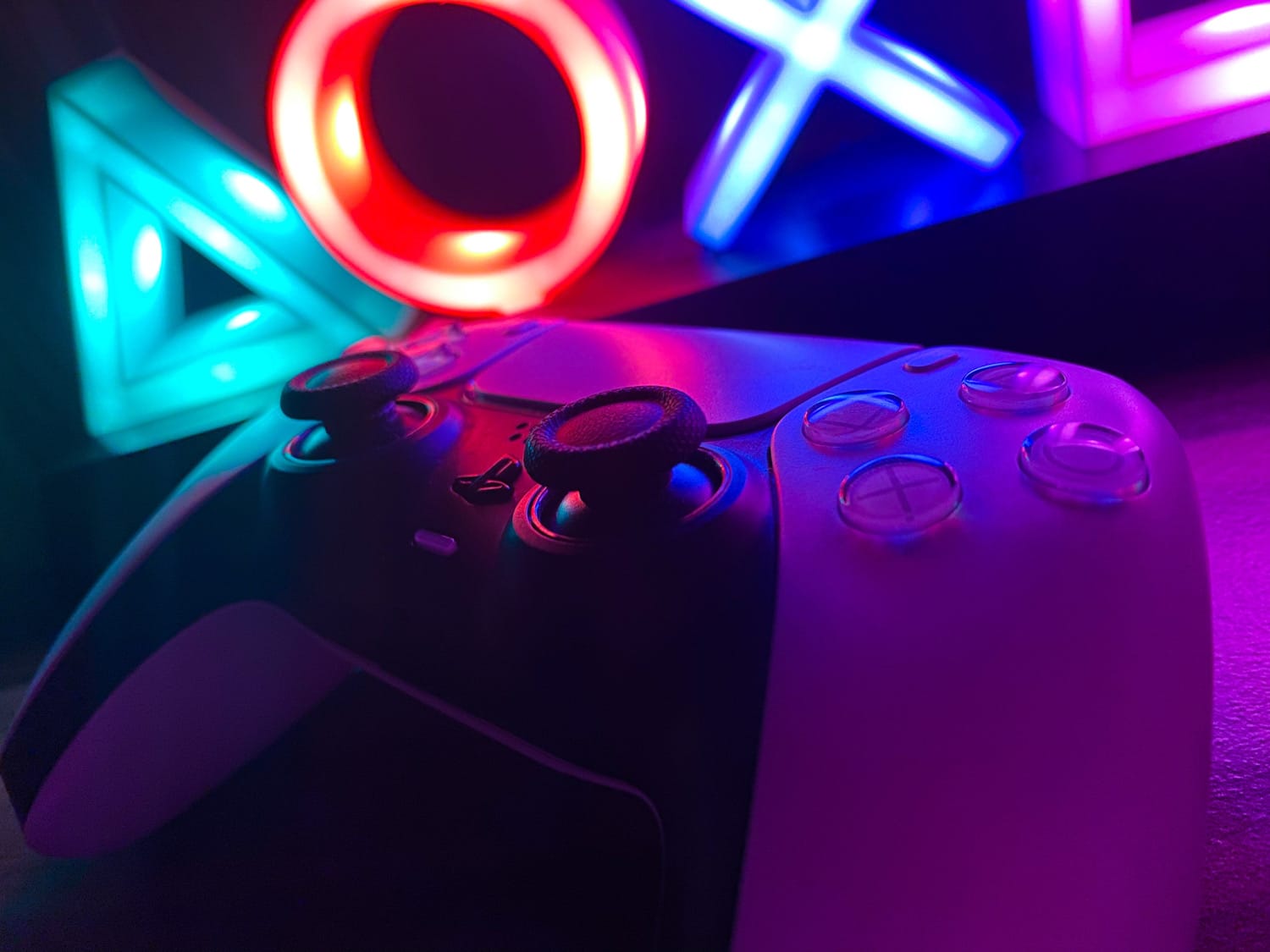 Weißer PS5-Controller vor einem Neonlicht-PlayStation-Logo