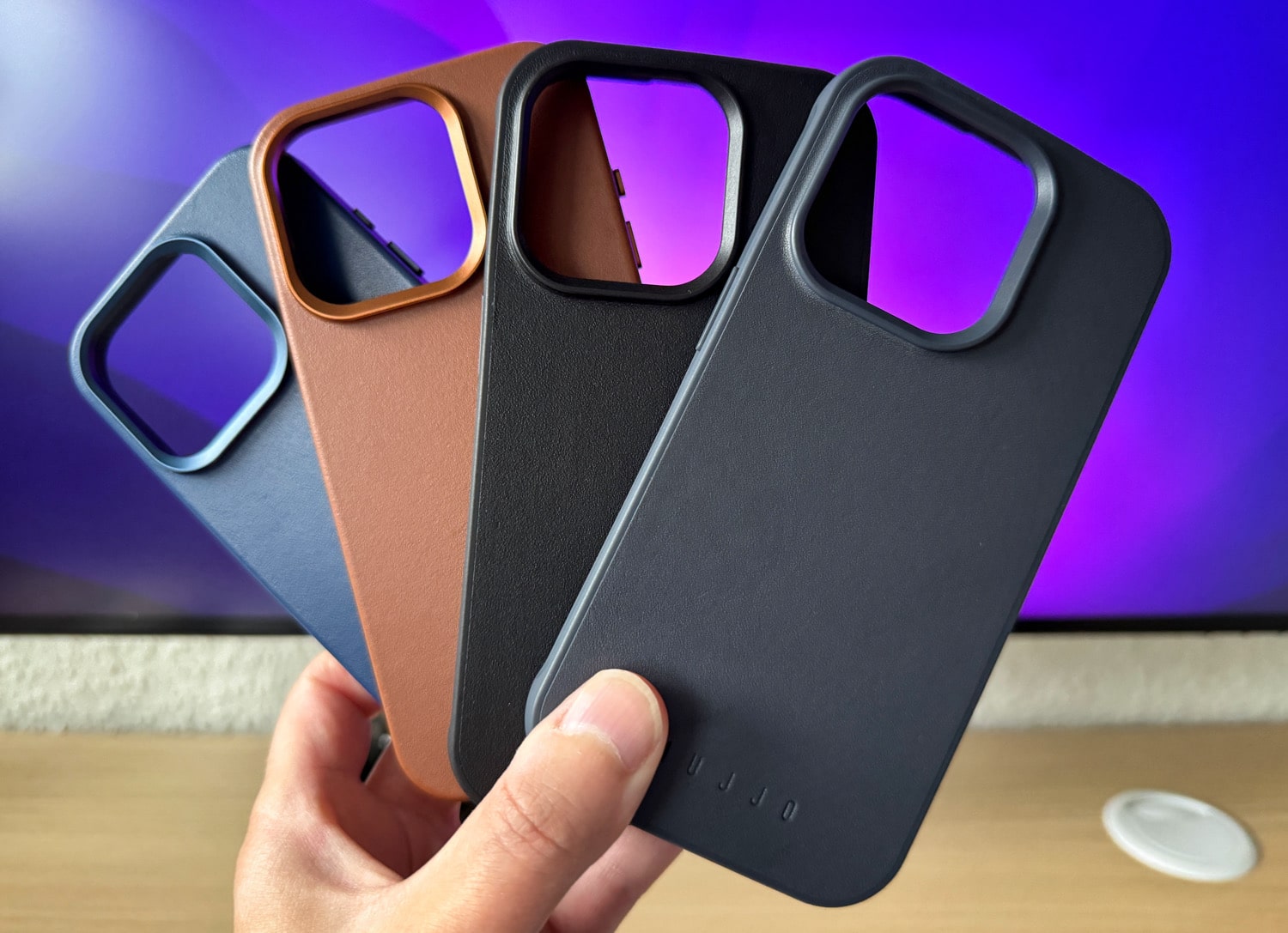 Vier Mujjo Cases für das iPhone 15 Pro in einer Hand