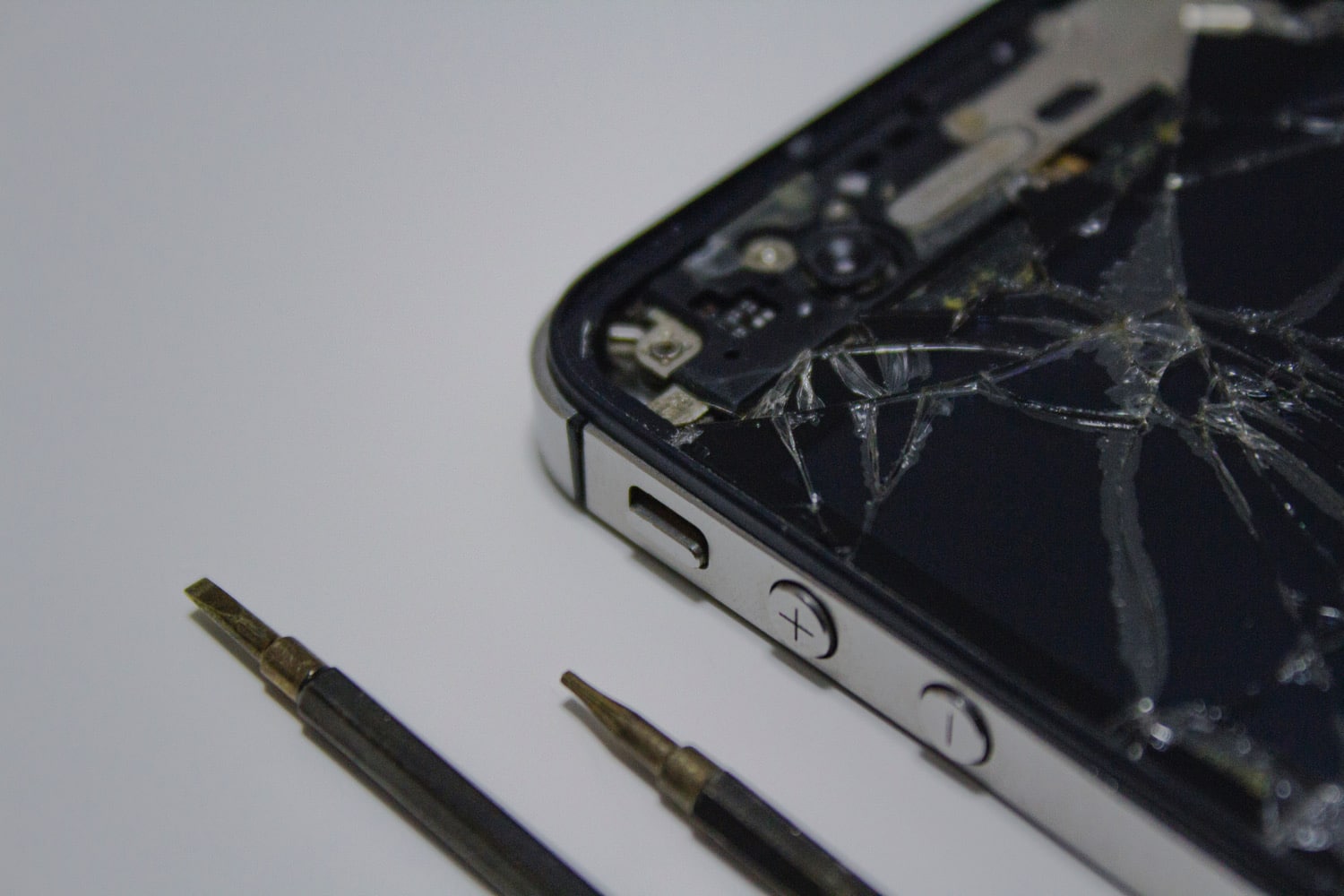Detailansicht eines kaputten iPhone-Displays mit kleinen Schraubendrehern