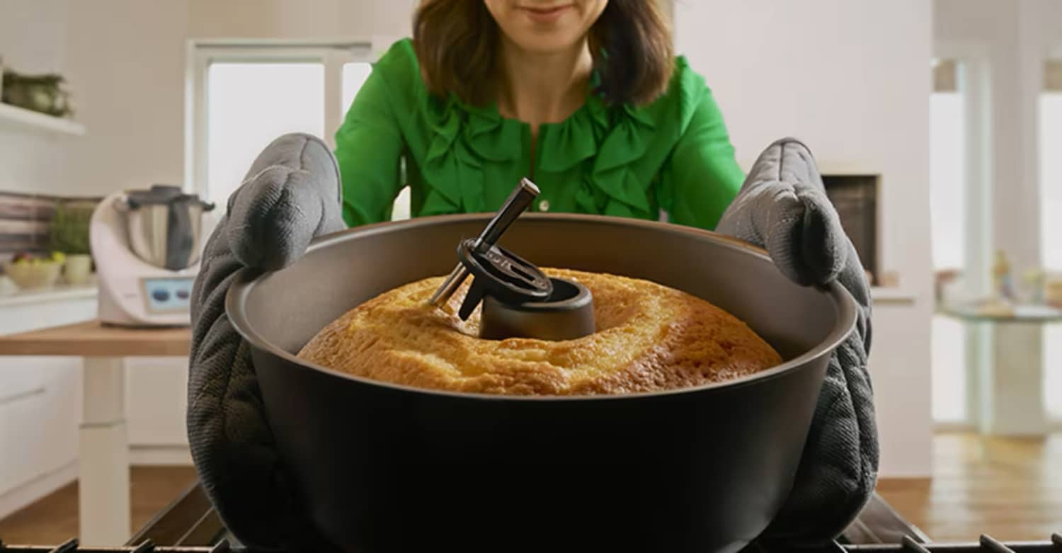 Eine Frau hält mit Handschuhen einen fertigen Kuchen samt Thermomix Sensor in den Händen