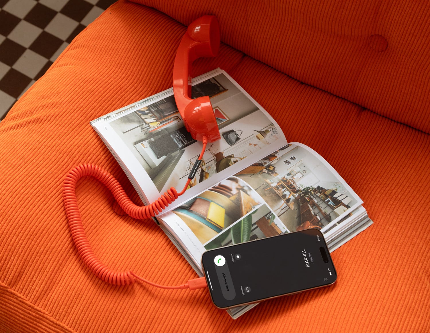 Orangefarbener Native Union POP Phone Telefonhörer liegt auf einem Sessel