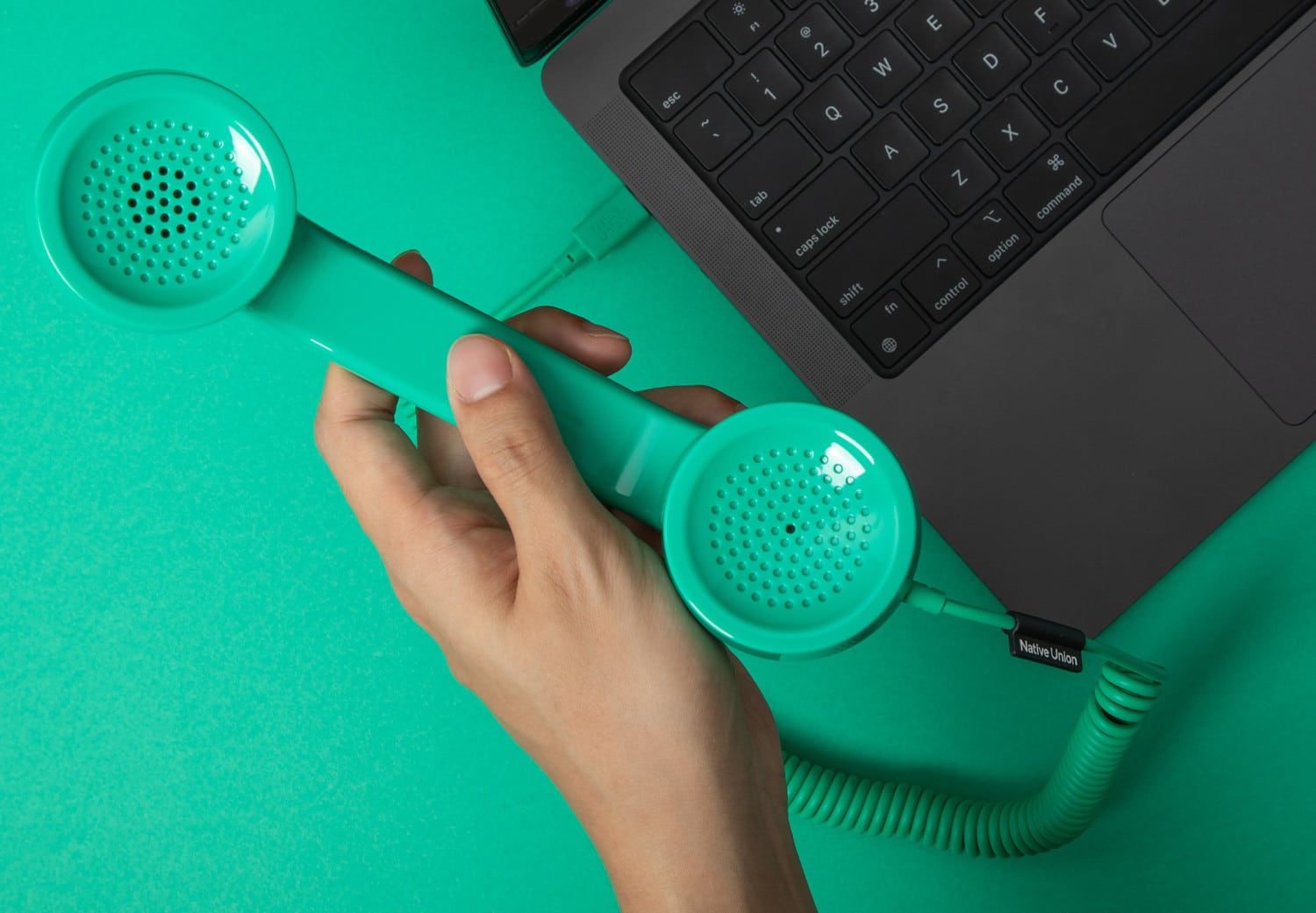 Eine Hand hält einen grünen Native Union POP Phone Telefonhörer