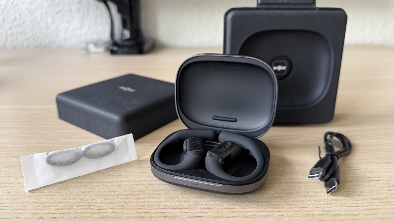 Shokz OpenFit Pro in Schwarz mit allem Zubehör auf einem Schreibtisch