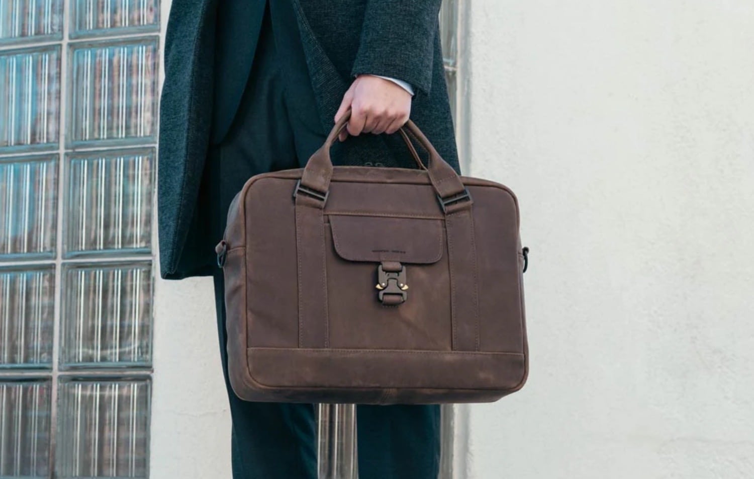 Eine Person im Mantel trägt die WaterField Lexington Leather Brief in Chocolate Brown in einer Hand