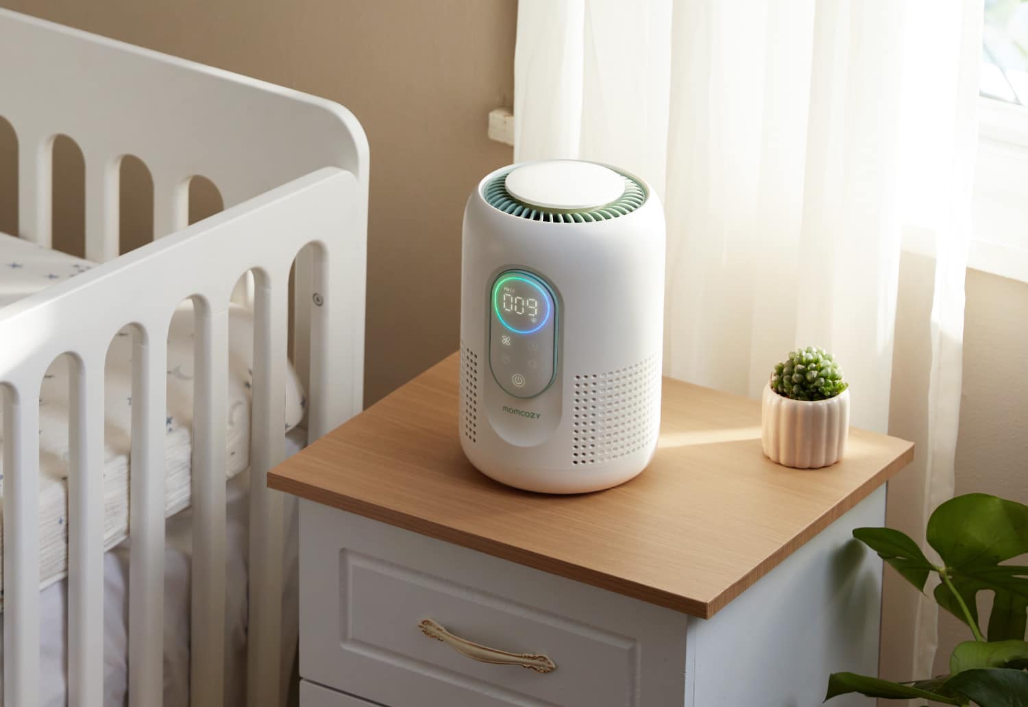 Momcozy CozyBreath steht auf einem Nachttisch neben einem Kinderbett