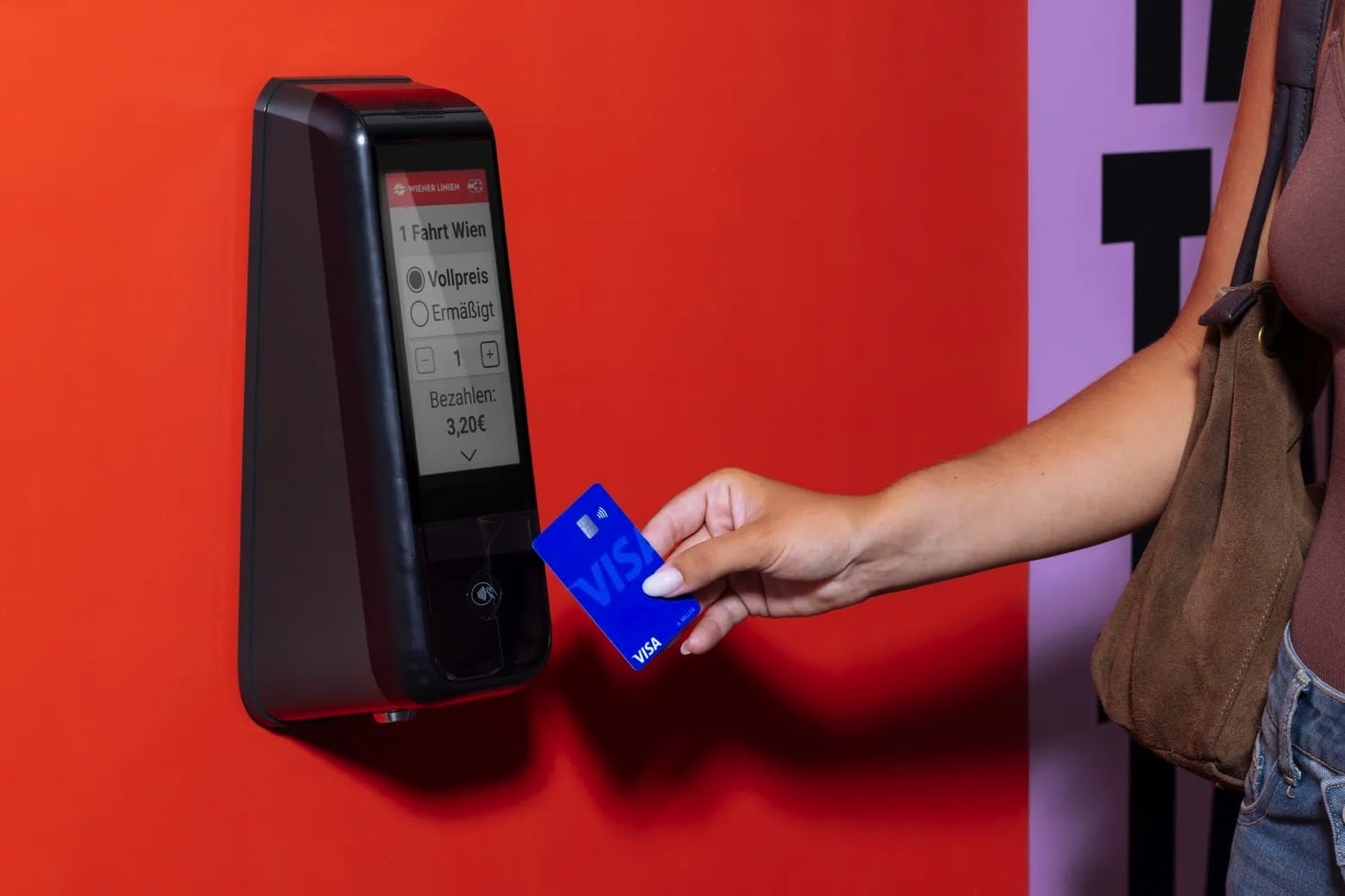 Eine Person hält eine Karte an ein Ticketterminal
