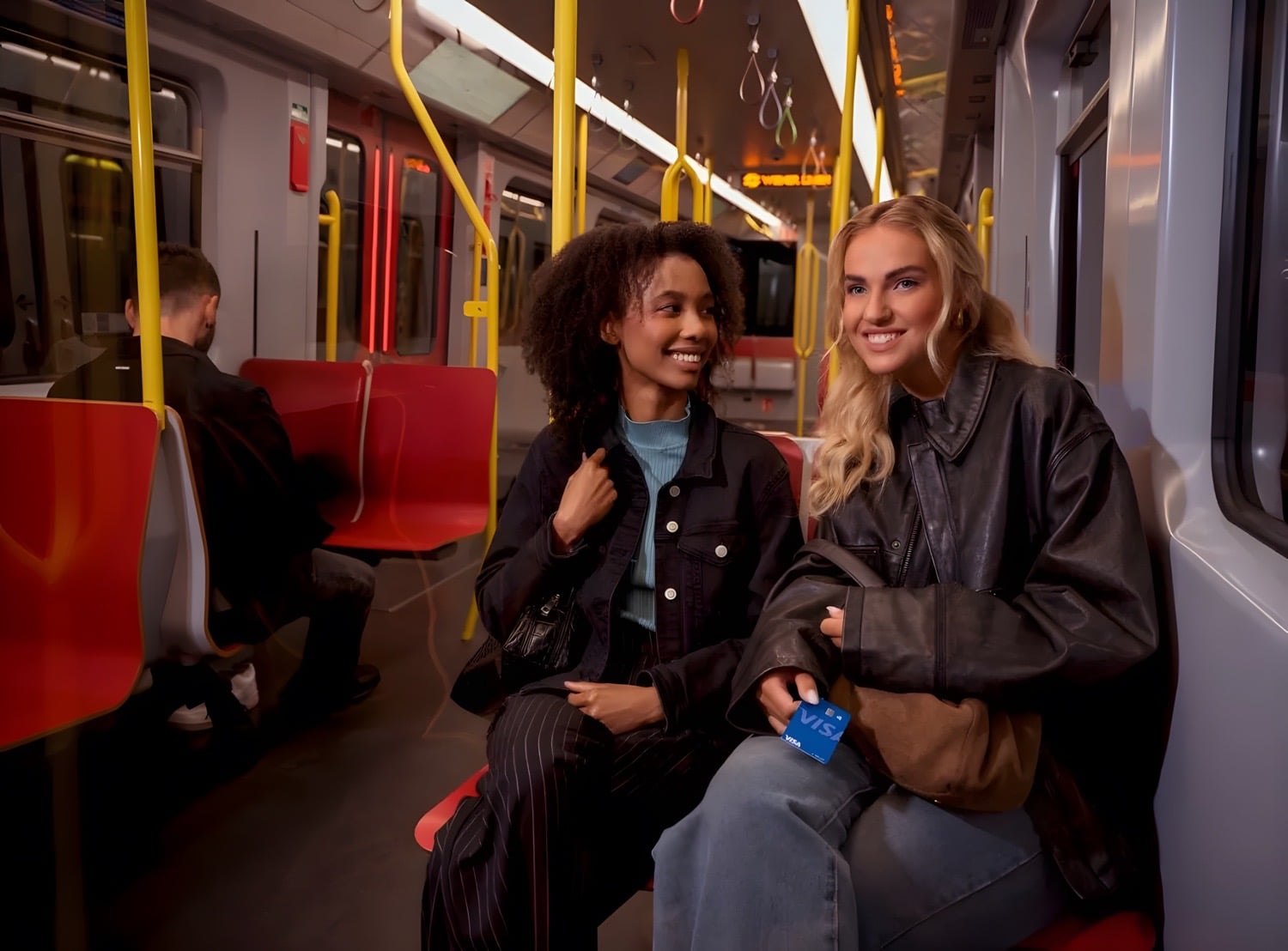 Zwei Personen sitzen nebeneinander lachend in einer Wiener U-Bahn