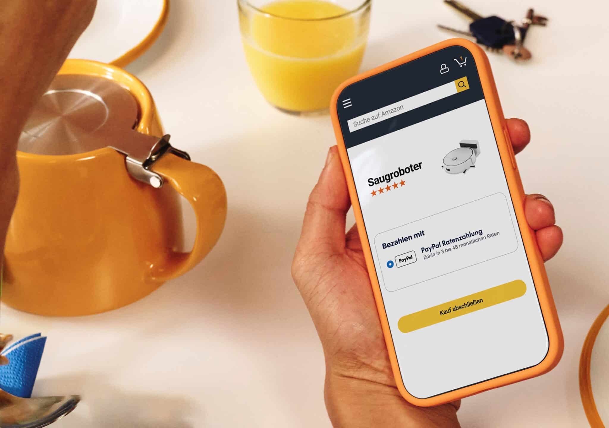 Eine Hand hält ein Smartphone mit einem Amazon-Bezahlvorgang auf dem Display in die Kamera.
