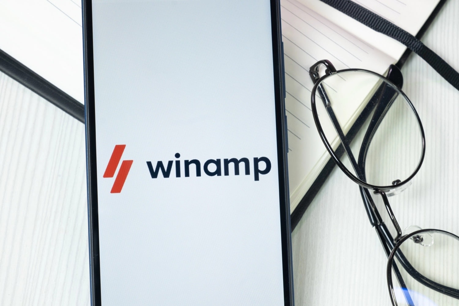 Winamp-Logo auf einem Smartphone, daneben eine Brille