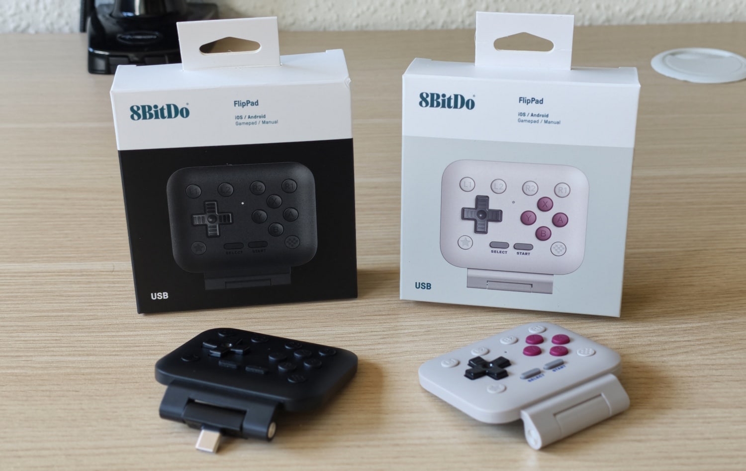 8BitDo FlipPad in den beiden verfügbaren Farbvarianten samt Verpackungen auf einem Schreibtisch