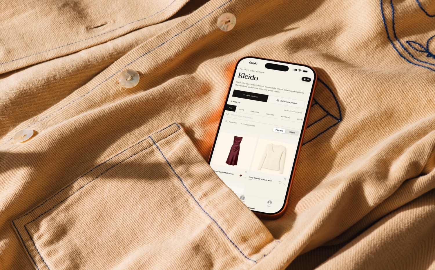 Kleido-App auf einem iPhone auf einem hellbraunen Hemd liegend