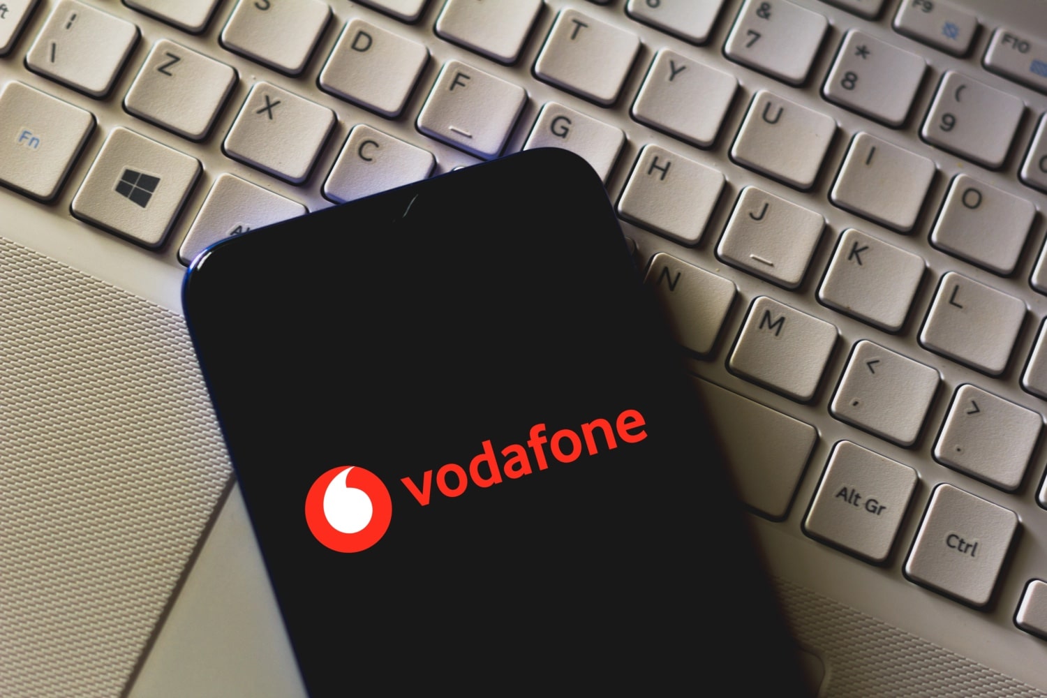 Smartphone mit Vodafone-Logo auf dem Screen liegt auf einer weißen Tastatur