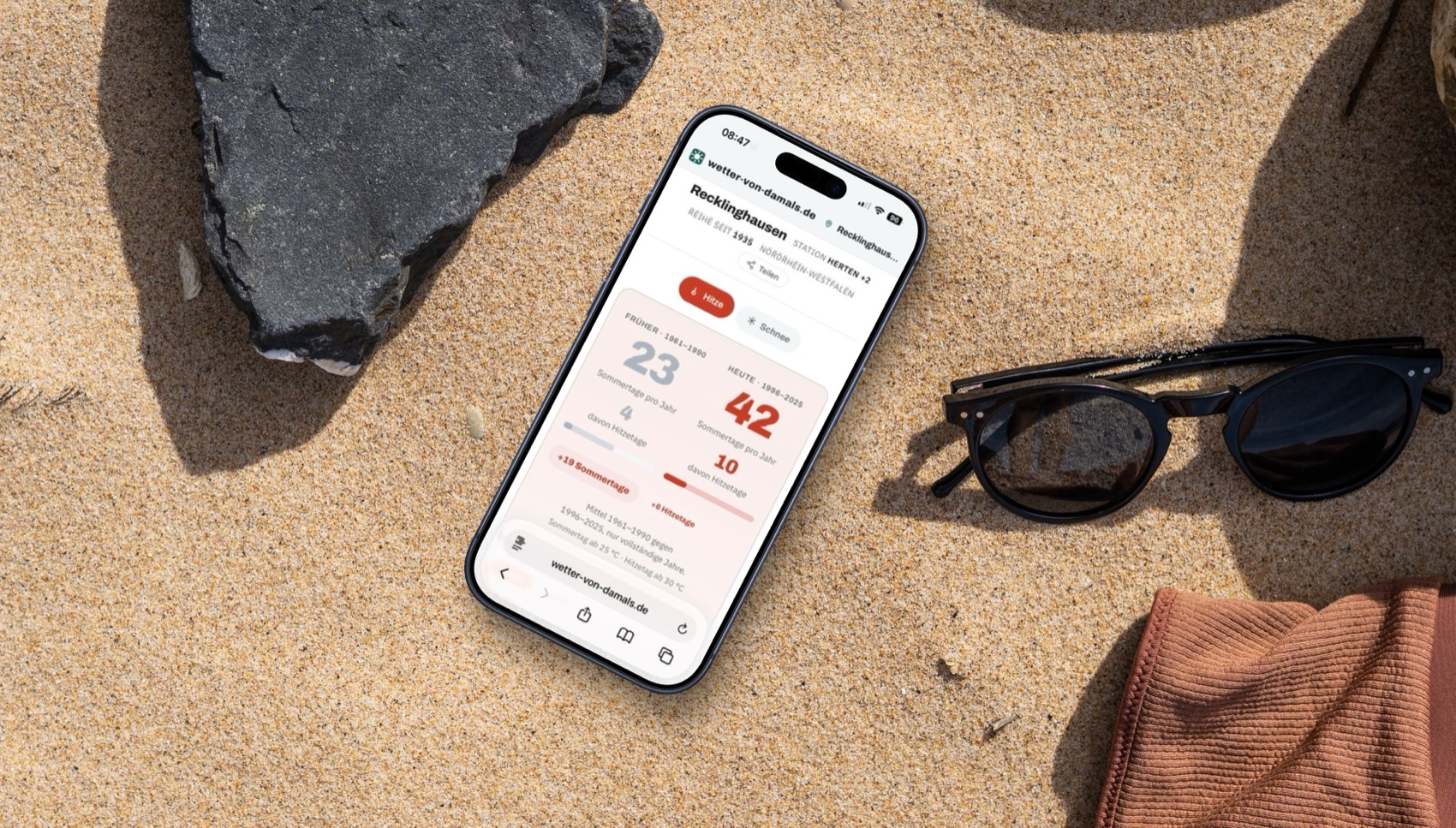 iPhone liegt im Sand und zeigt Webseite an