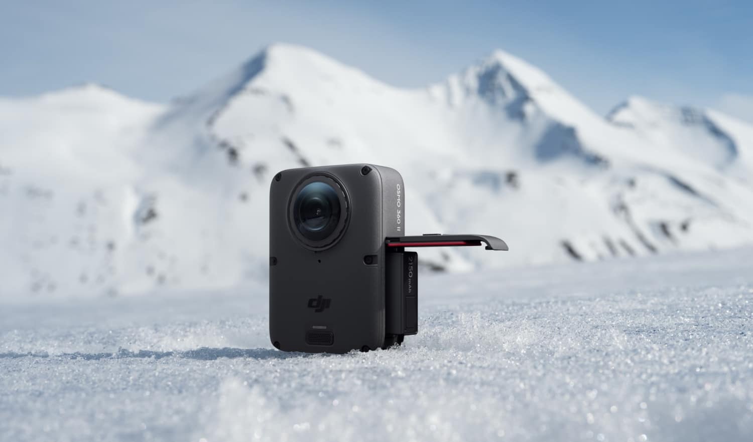 DJI Osmo 360 II steht mit offenem Akkuverschluss in einer Berglandschaft
