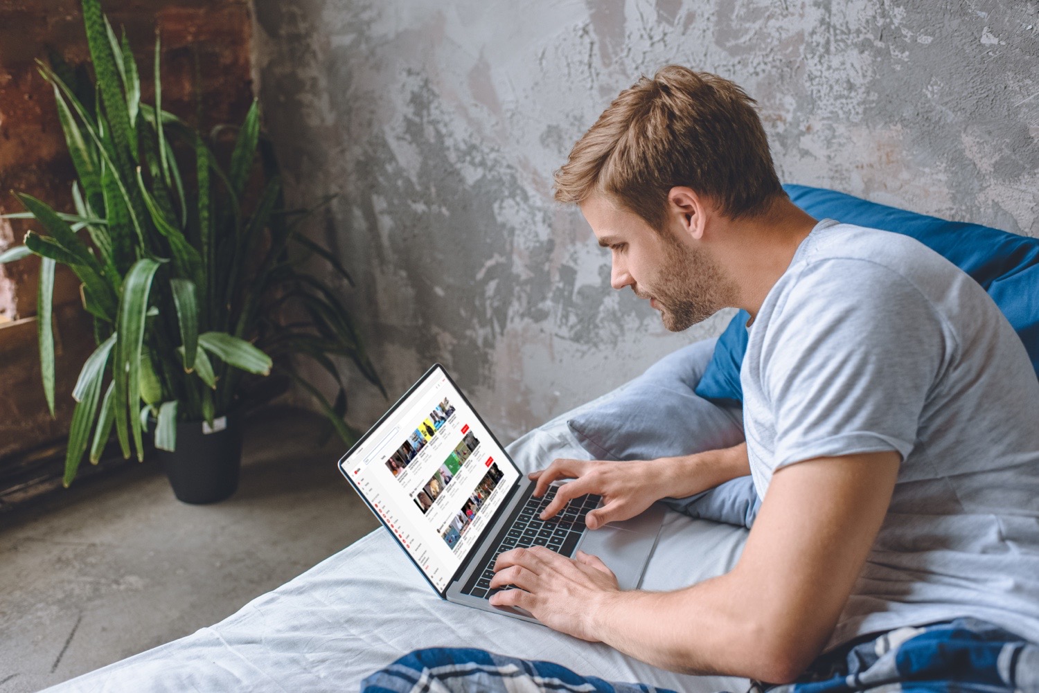 Eine Person sitzt auf einem Bett und schaut sich die YouTube-Website an